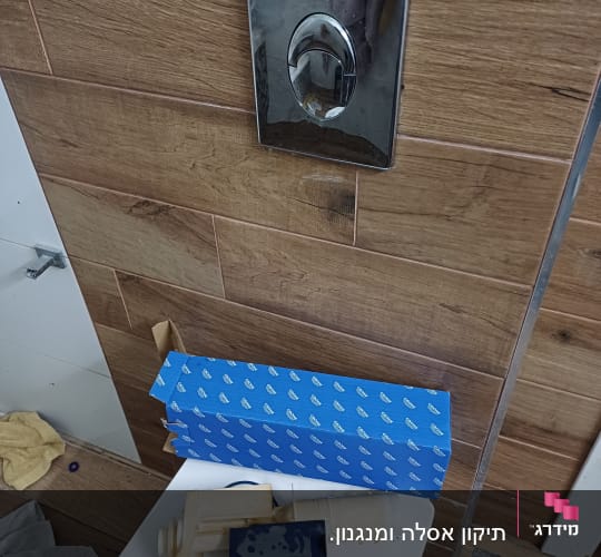 חלקי אסלה וכלי עבודה על רצפה בחדר אמבטיה